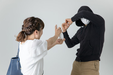 犯罪者に防犯スプレーをかける女性
