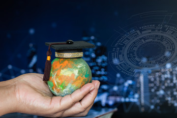 Education world knowledge ideas. Graduation cap on Businessman holding models earth globe in hands on blur HUD graphic ioc city network background. Concept of global business study abroad educational