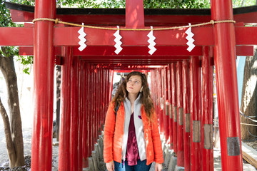 Young woman tourist walking under torii gates at Hanazono shrine temple in Shinjuku, exploring city...