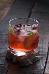 cherry and lime cocktail on a wooden floor with garnish