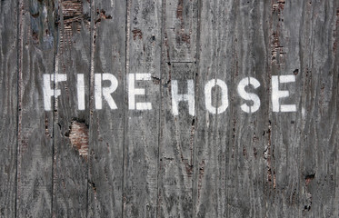 Close up full frame view of a stenciled sing FIRE HOSE on a weathered wooden box on a wall