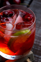 cherry and lime cocktail on a wooden floor with garnish