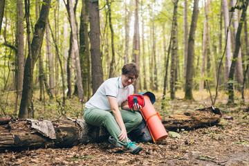 Young woman having trouble feeling knee pain during travel in forest. Injury on way to camp. female tourist got leg injury in forest and gets hurt. Health problem in journey. Theme Insurance Company
