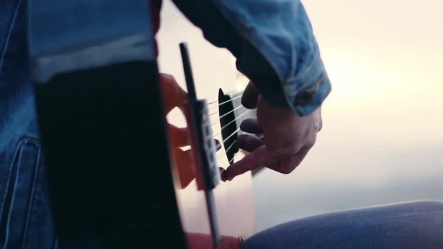 Singer playing the guitar at sunset on the mountain