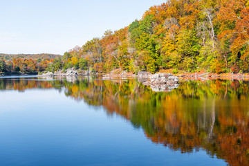 Great Falls in Maryland with yellow orange colorful autumn foliage leaves on trees with reflection in water surface of river canal or lake