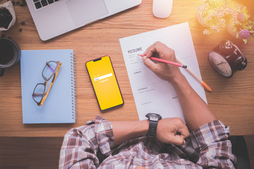 wood table with businessman filling resume information.