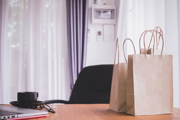office desk with paper bag shop and coffee cup in room, concept of online shopping.