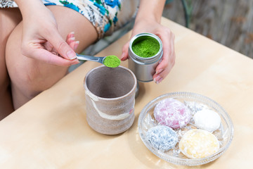 Green matcha and mochi rice cake Japanese dessert colorful daifuku with woman girl hand preparing...