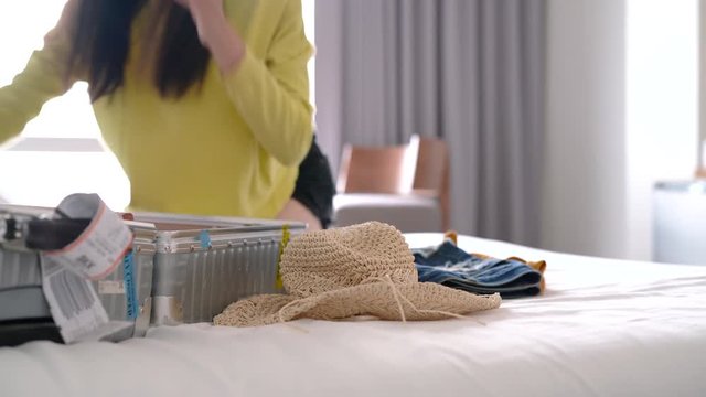 Beautiful Asian traveler woman packing clothes suitcase in hotel her ready check-out for travel next trip.