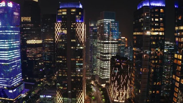 JAKARTA, Indonesia - June 26, 2019: Aerial landscape of modern buildings with beautiful night lights in central business district. Shot in 4k resolution from a drone flying from left to right