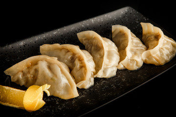 macro view asian gyoza dumplings with orange slice on plate