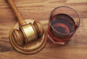 Glass with whisky and judge gavel, alcohol and crimes concept