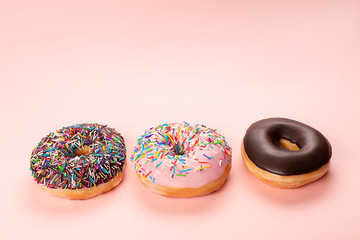 Three tasty doughnuts on pink background.