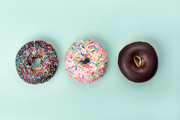 Three tasty doughnuts on turquoise background.