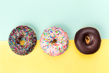 Three tasty doughnuts on turquoise background.