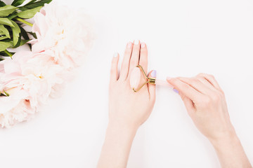 Gua sha massage jade roller in woman hands. Trendy beauty treatment. Flat lay, top view.