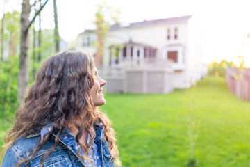 Young woman smiling homeowner in Northern Virginia, Fairfax county residential neighborhood in spring or summer by house backyard