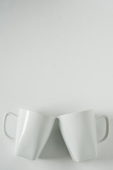 White coffee mugs on white background clinking in cheers with empty copy space