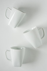 3 white coffee mugs on white background scattered with empty copy space