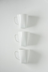 3 white coffee mugs on white background in a vertical row, empty copy space