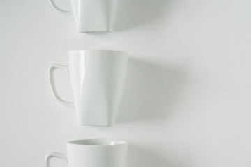 White coffee mugs on white background in a vertical row with empty copy space