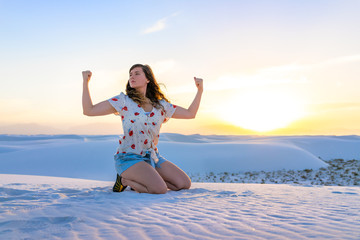 Woman flexing sitting in white sands dunes national monument nature in New Mexico view of sunset