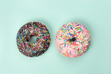 Two tasty doughnuts on turquoise background.