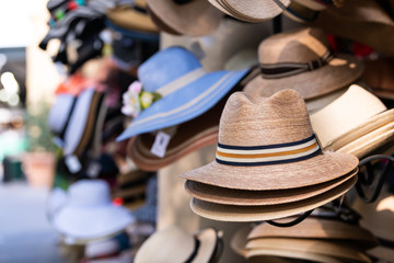 Stack stacked fedora man straw hats on retail display of street vendor store with many colors in...