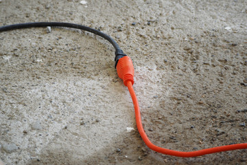 Close-up of a cable conductor extension with a connected tool on the cement floor.