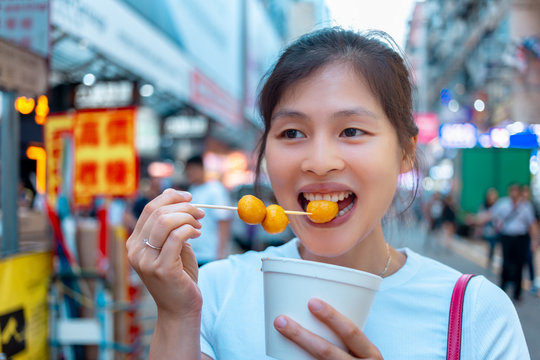 Asian young female eating famous street food - fish ball, in Hong Kong