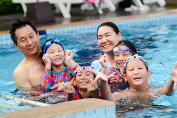 Happy Asian family enjoying in pool together, lifestyle concept.