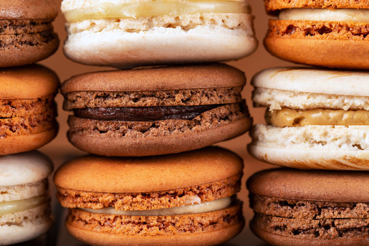 Piles of brown and white french macarons or macaroons, (chocolate, coffee, toffee, salted caramel and vanilla).