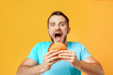 Man with burger on color background