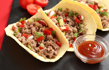 Slate plate with tasty fresh tacos and sauce on color background, closeup