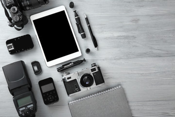 Tablet computer and set of photographer's equipment on wooden background