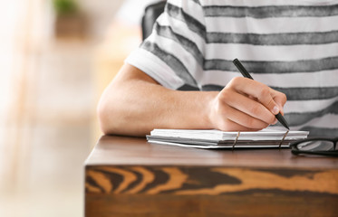 Male student writing something in notebook, closeup