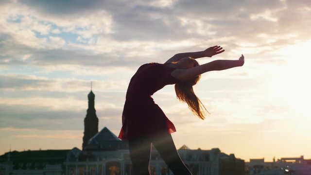 Attractive young woman performing ballet pas in the outdoors