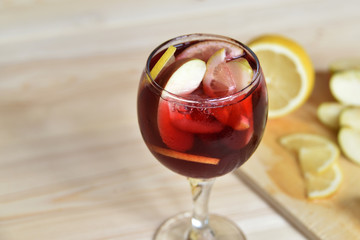 A glass of cold refreshing sangria with ice and fruit in water droplets.