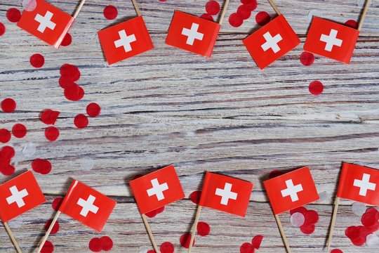 independence day Switzerland, August 1. Federal holiday in honor of the founding of the Swiss Confederation. day of the Confederacy. mini flags with confetti on wooden background. horizontal