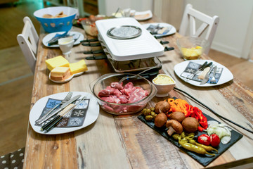 Swiss or Dutch raclette table filled with ingredients for a celebratory evening like Christmas or New Years Eve