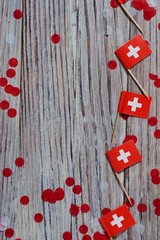 independence day Switzerland, August 1. Federal holiday in honor of the founding of the Swiss Confederation. day of the Confederacy. mini flags with confetti on wooden background. vertical