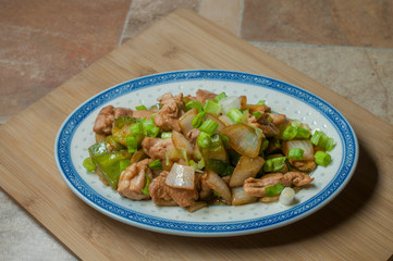Oriental chicken with vegetables, onion, green pepers, and chopped chives on top, with a touch of soy sauce and ginger.