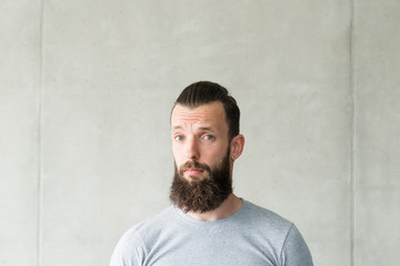 Empathy and compassion. Portrait of bearded hipster guy standing over gray wall background. Copy space.