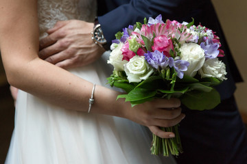 Obraz na płótnie Canvas Bride and groom are holding a wedding bouquet. Hands newlyweds and bridal bouquet. Wedding bouquet in the hands of the newlyweds. Bride and groom hands near and hold flowers.