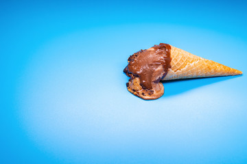coffee flavor ice cream cone in a melting process on a blue background