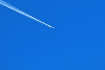 青空バックに飛ぶジェット機と飛行機雲