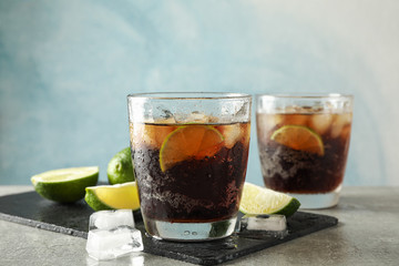 Glasses with cold cola and citrus on grey table, space for text