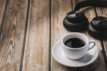 cup of coffee, headphones and beans on wooden table