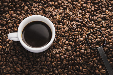 cup of coffee and spoon on brown beans 