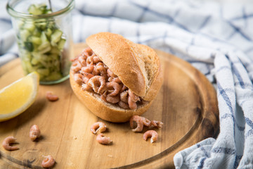 Norddeutsche Friesische Nordseekrabben in Glas Schale mit Brötchen, Gurkensalat und Zitronen auf Holz Brett